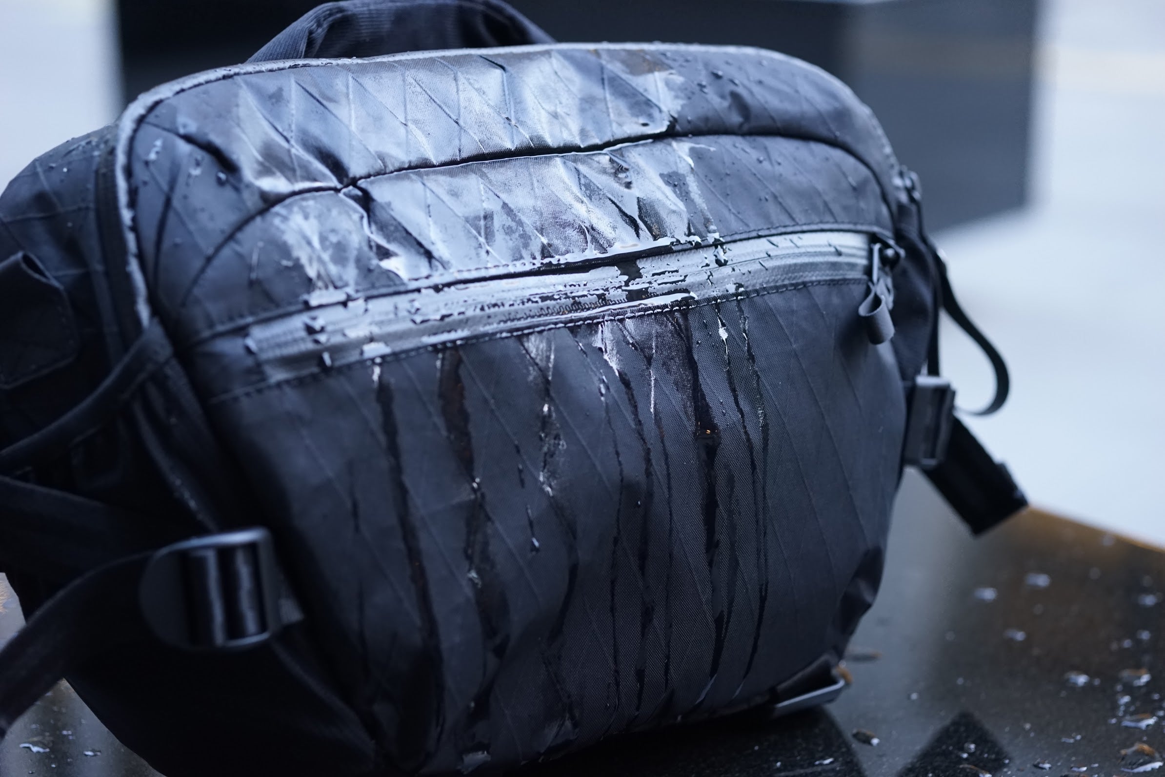Water flowing on stormproof black pro camera sling bag