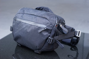 Compact black camera sling bag with x-Pac fabric on a black surface